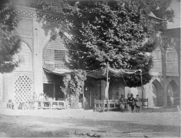 عکسی قدیمی به رنگ سیاه و سفید که یک قهوهخانه را در کنار خیابان چهارباغ اصفهان نشان میدهد. این قهوهخانه دارای دیوارهای کاشیکاریشده و سقف چوبی است. در این تصویر چند مرد با لباسهای سنتی دیده میشوند که در حال نشستن و نوشیدن قهوه هستند، که تصویری از یک گردهمایی اجتماعی در گذشته را به نمایش میگذارد.